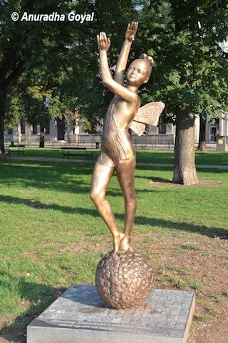 Golden colored sculpture of a girl in the city park