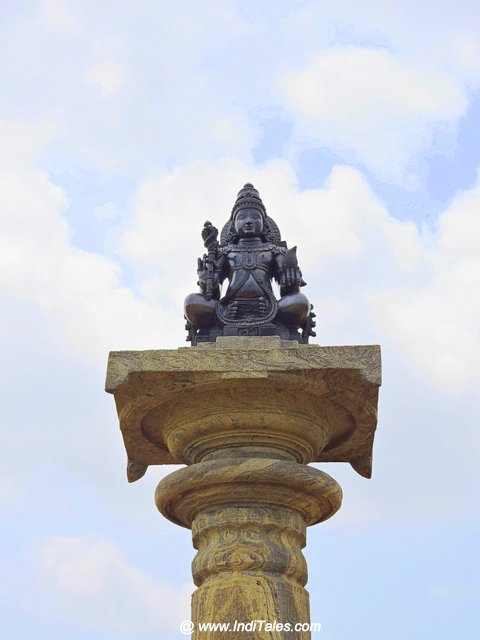Yaksha atop a pillar facing the Bahubali